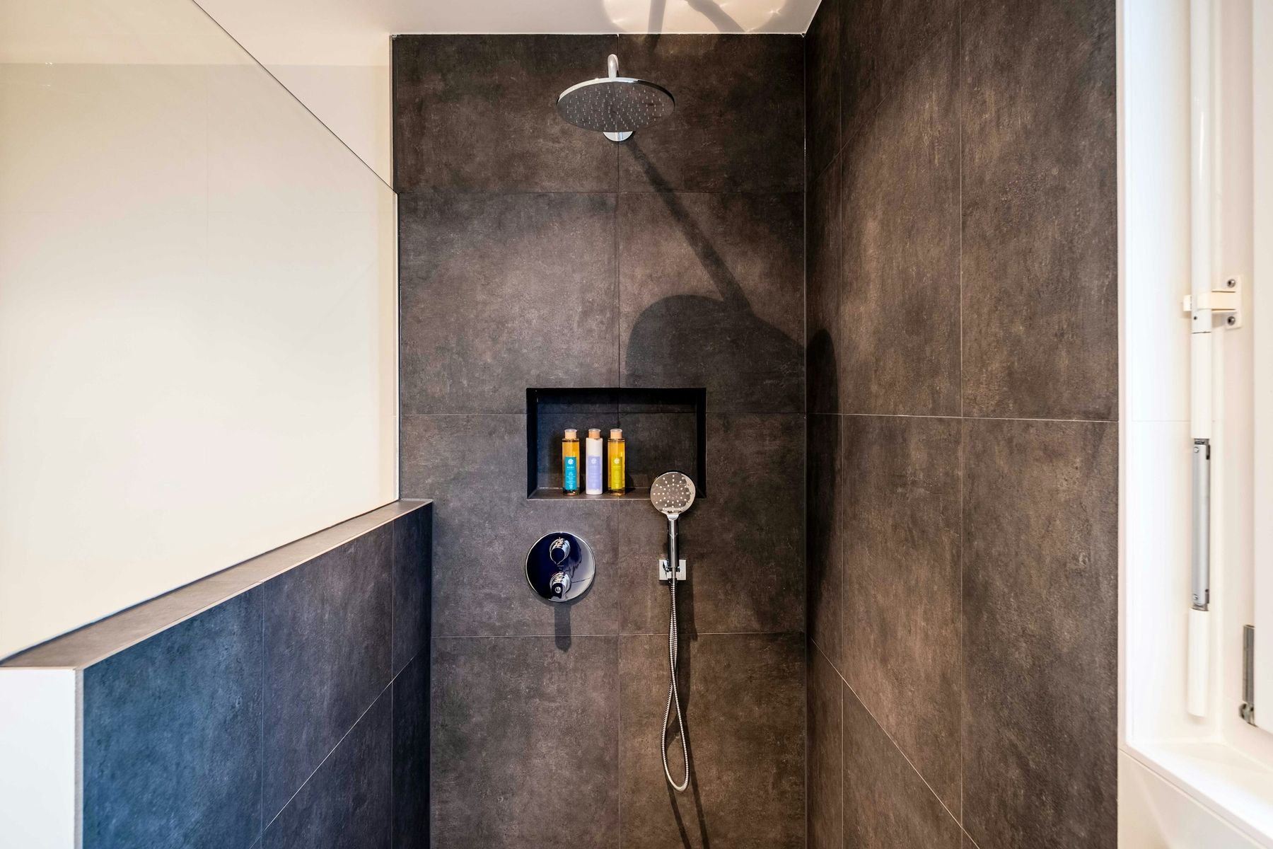 Douche à l’italienne en carrelage sombre avec niche murale et pommeau de tête