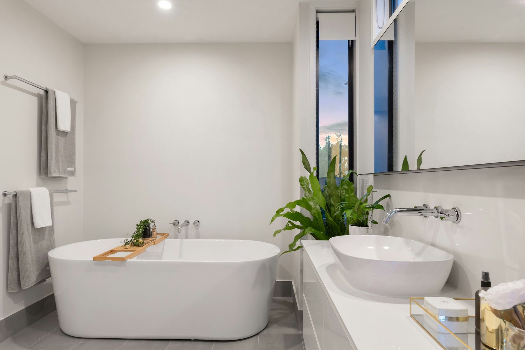 Salle de bains blanche rénovée : baignoire îlot, vasque posée, robinetterie murale